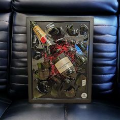 a black framed photograph with wine bottles and glasses in it on a blue leather chair