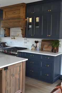 a large kitchen with blue cabinets and white counter tops, wood accents on the island