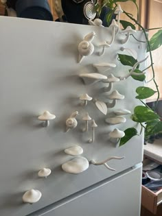 a white refrigerator freezer sitting next to a potted plant on top of it