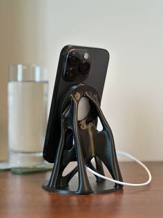 an iphone is plugged in to a charging station on a wooden table next to a glass of water