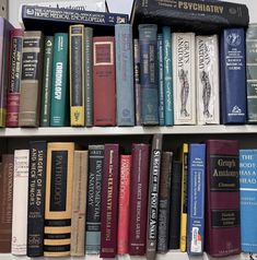 several rows of books sitting on top of a white book shelf next to each other