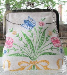 a white purse with flowers and butterflies on it sitting on top of a glass table