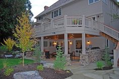 a house with stone steps leading up to the front porch and covered patio area, surrounded by trees