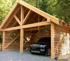 a car is parked in front of a wooden garage with an attached carport and roof