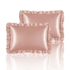 two pink pillows with ruffled edges on a white background, one is shiny and the other is plain