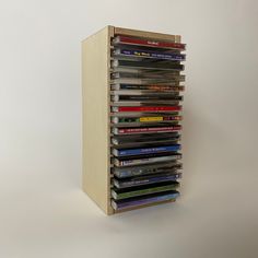 a stack of dvd's sitting on top of a wooden shelf next to a white wall