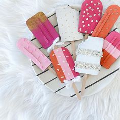 popsicles are arranged on a plate with pink, orange and gold sticks sticking out of them