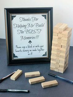 there is a pile of wooden blocks next to a framed sign and pens on the table