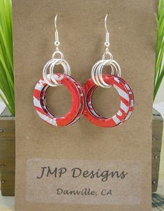 pair of red and white hoop earrings on display in front of card board with plant