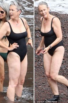 two women in swimsuits are walking on the beach and one is wearing black