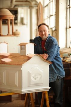 a man standing next to a white doll house