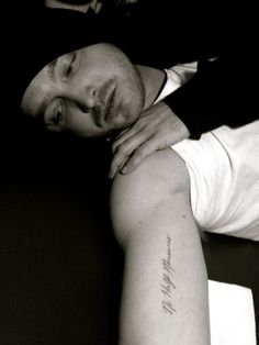 a man with a tattoo on his arm is laying down and looking at the camera