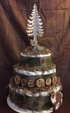 a three tiered cake decorated with wood slices and trees on the top, surrounded by moss