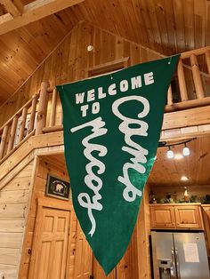 a welcome sign hanging from the side of a wooden building