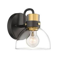 a wall light with a clear glass shade on it's face and gold accents