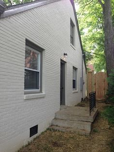 a white house with steps leading up to the front door and side yard area next to it