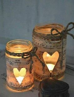 two mason jars with lights in them sitting on top of sheet music notes and a cookie