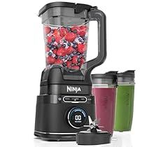 the ninja blender is full of fruit and vegetables, with two cups next to it