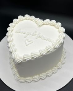 a white heart shaped cake sitting on top of a plate