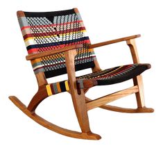 a wooden rocking chair with multicolored fabric on it's seat and back