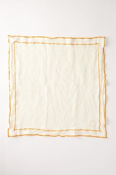 an orange and white napkin on top of a white table with yellow trimmings