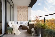 a balcony with couches and potted plants on it