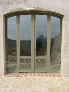 an arched glass door in front of a stone building with large windows on each side