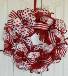 a red and white christmas wreath hanging on a door