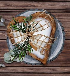 a heart shaped piece of bread on a plate with greenery tied around it and some leaves