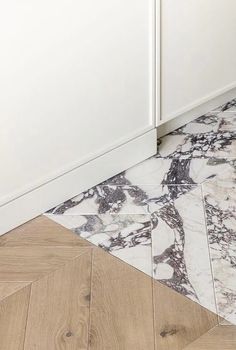 a kitchen with white cabinets and marble flooring on the side of the counter top