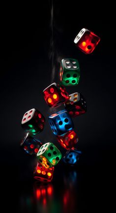 several dices with different colored lights are flying in the air on a black background