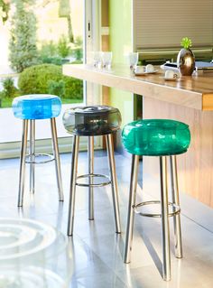 three stools sitting in front of a counter with a glass top on each one