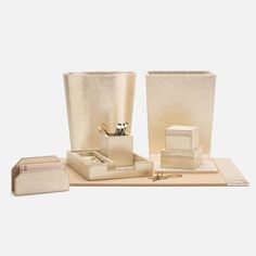 a set of gold colored items including a pen, ring box and napkins on a white background