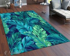 a living room area rug with blue and green tropical leaves on the floor in front of a couch