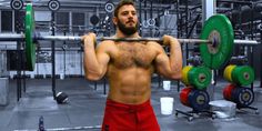 a shirtless man holding a barbell in a gym