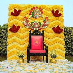 a red chair sitting in front of a yellow wall with flowers and decorations on it