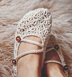 a woman's feet wearing crocheted shoes on top of a furry rug