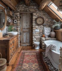 a rustic bathroom with stone walls and wood floors, an old bathtub, sink, toilet and rug