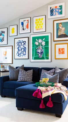 a living room filled with lots of pictures on the wall above a blue couch and coffee table