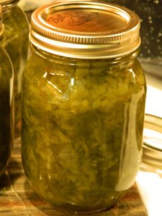 two jars filled with pickles sitting on top of a table