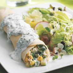 a white plate topped with a burrito covered in toppings and veggies