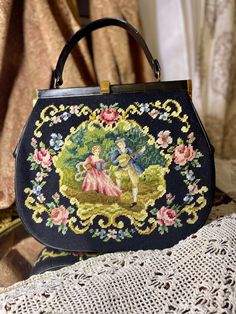 A gorgeous large needlepoint handbag in a black pattern with a beautiful embroidered pattern of a lovely Victorian style couple with flowers with a black background. It has a shapely black leather handle.  It is leather lined with 2 inner pockets. Victorian Black Rectangular Bag, Formal Embroidered Tapestry Bag, Elegant Black Shoulder Bag With Floral Embroidery, Couple With Flowers, Style Couple, Embroidered Handbag, Vintage Purses, Vintage Purse, Victorian Style