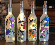 three wine bottles with flowers painted on them are sitting on a table next to each other