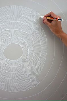 a person is writing on a wall with white circles and lines drawn in the center