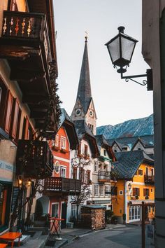 an old european street with buildings and a church steeple in the background at sunset