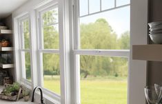 an open kitchen window overlooking a green field