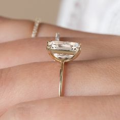 a close up of a person's hand with an engagement ring on their finger