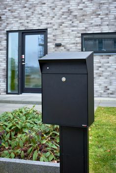 a black mailbox sitting in front of a brick building with the number 12 on it