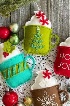 three christmas mugs on a doily with ornaments around them and the words holly jolly