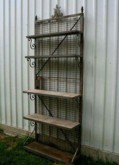 an old metal shelf with three shelves on it in front of a white corrugated wall